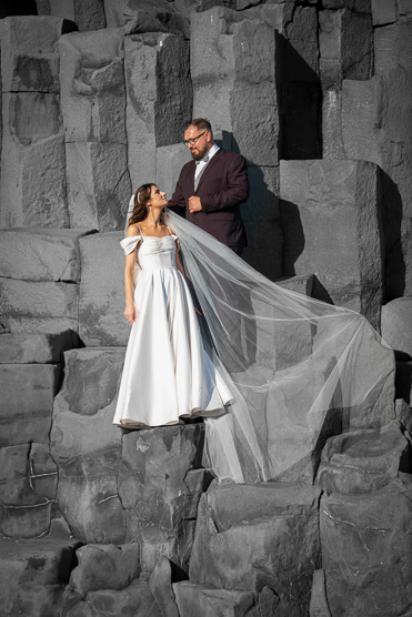 Bride and groom on basalt columns with veil in the wind